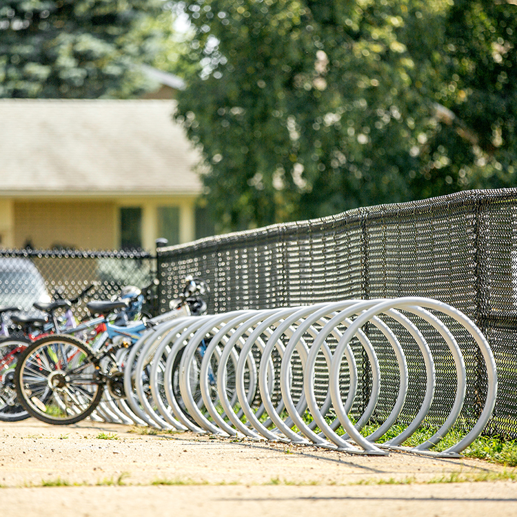 stainless steel commercial outdoor bike racks are placed in the parking area of a national park entrance