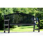 black metal outdoor bench/ patio bench/ garden bench sits quietly and surrounded by greeneries on a beautiful summer day