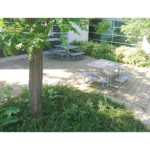 2 outdoor patio tables for dining are installed by a community center in the backyard