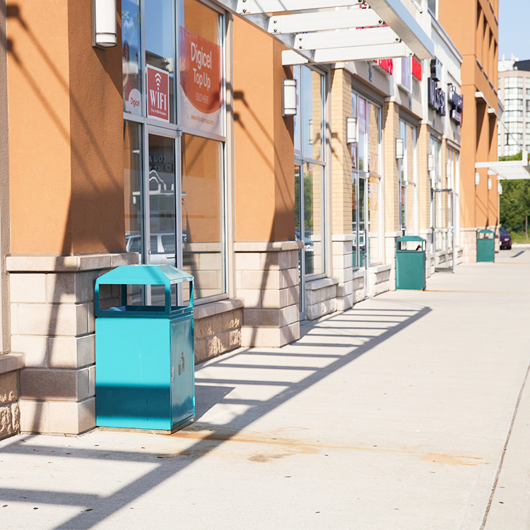 commercial street trash bins are installed at storefronts on a commercial street in downtown Toronto