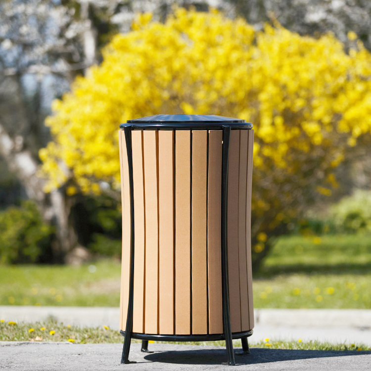 recycled plastic outdoor park commercial trash can with a powder coated metal frame standing in a park in a mid-fall afternoon