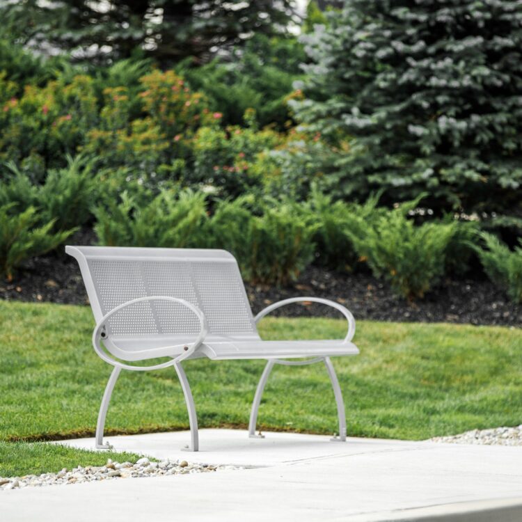 silver metal commercial outdoor park bench fits well with the park landscaping and the surrounding