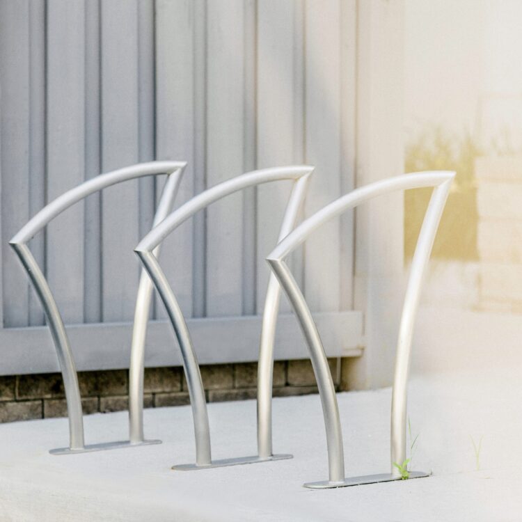 3 stainless steel city bike parking rack is in the sunlight in the community park in downtown Toronto