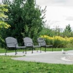 black commercial outdoor metal memorial and park benches in a park surrounded by greeneries. This bench is also widely chosen for residential garden applications